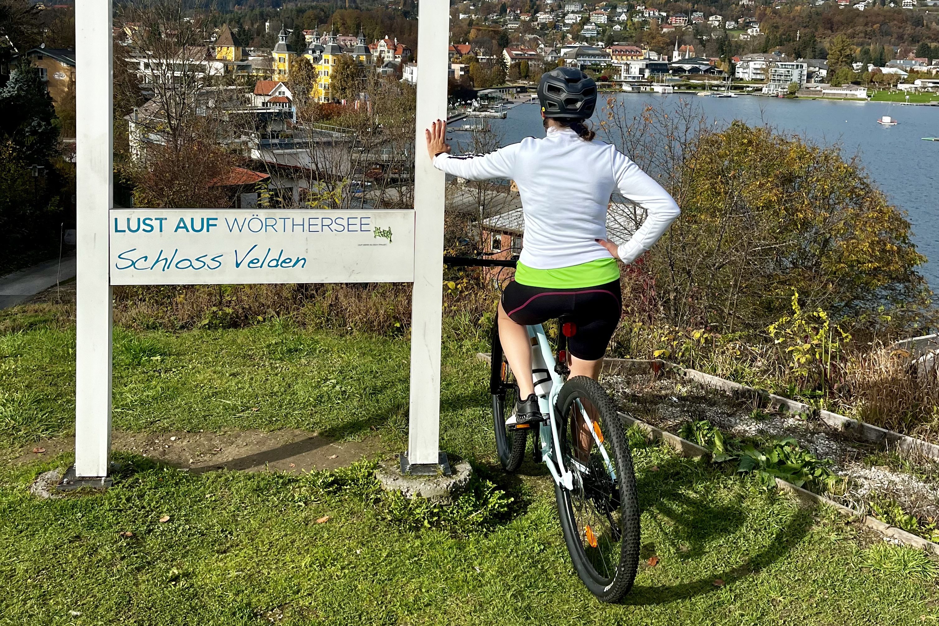 Marina Sophie Flasch beim Radfahren und Wörthersee, Schlosshotel Velden im Hintergrund
